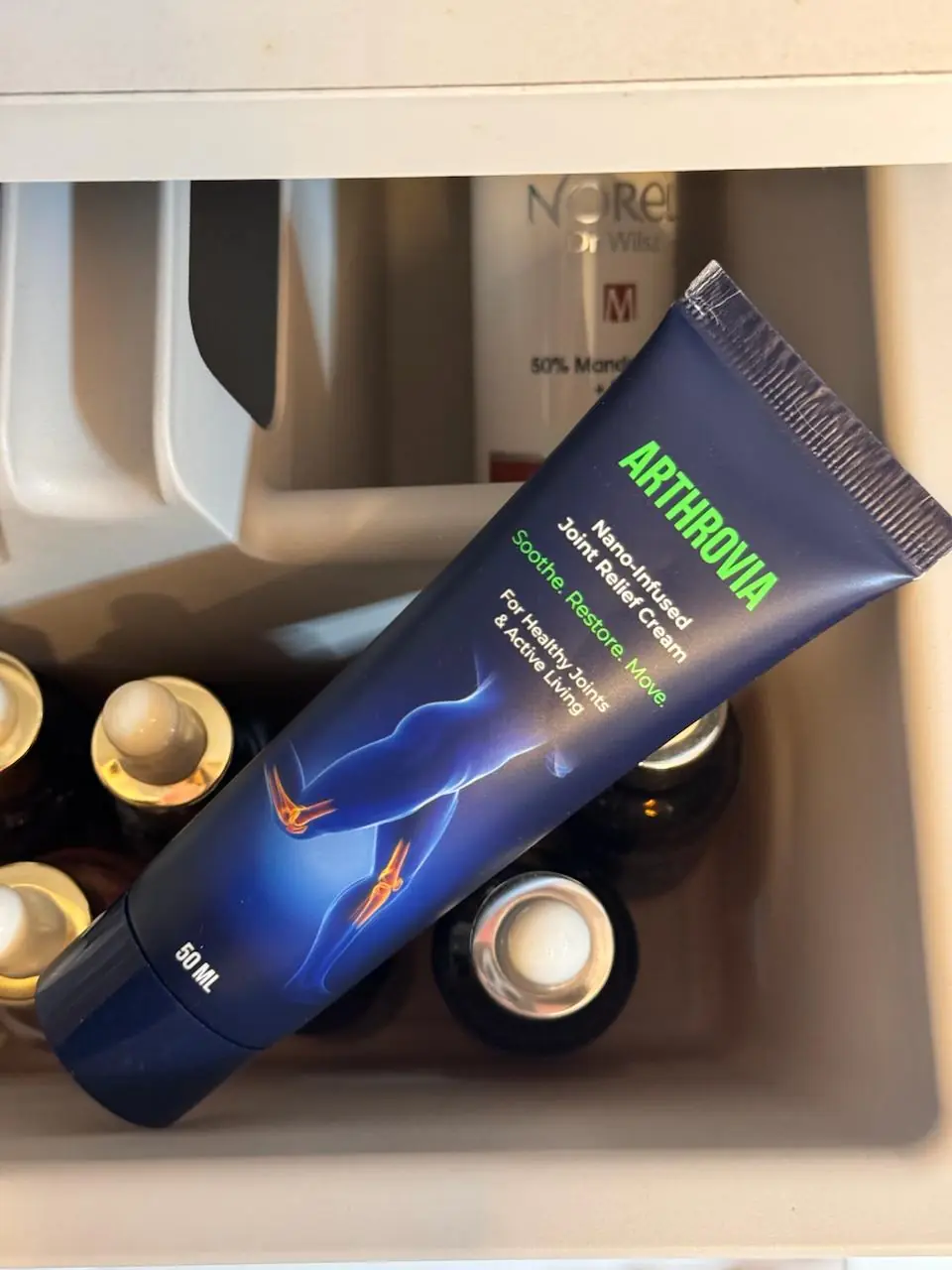 Tuba Arthrovia 50 ml v odprtem predalu med stekleničkami kozmetike