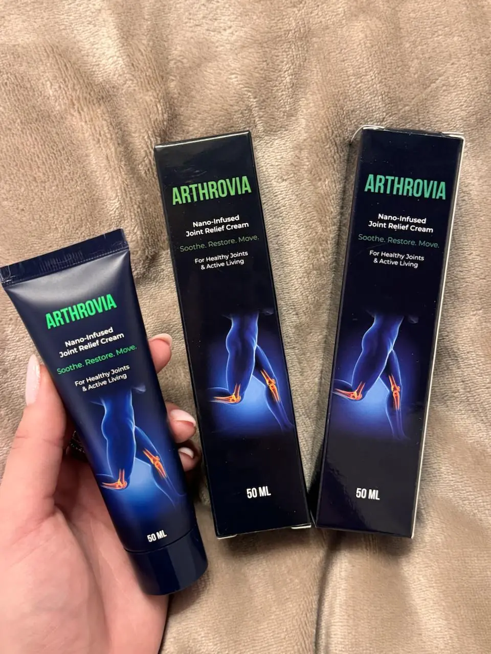 Tuba Arthrovia 50 ml v roki in dve škatli na bež odeji